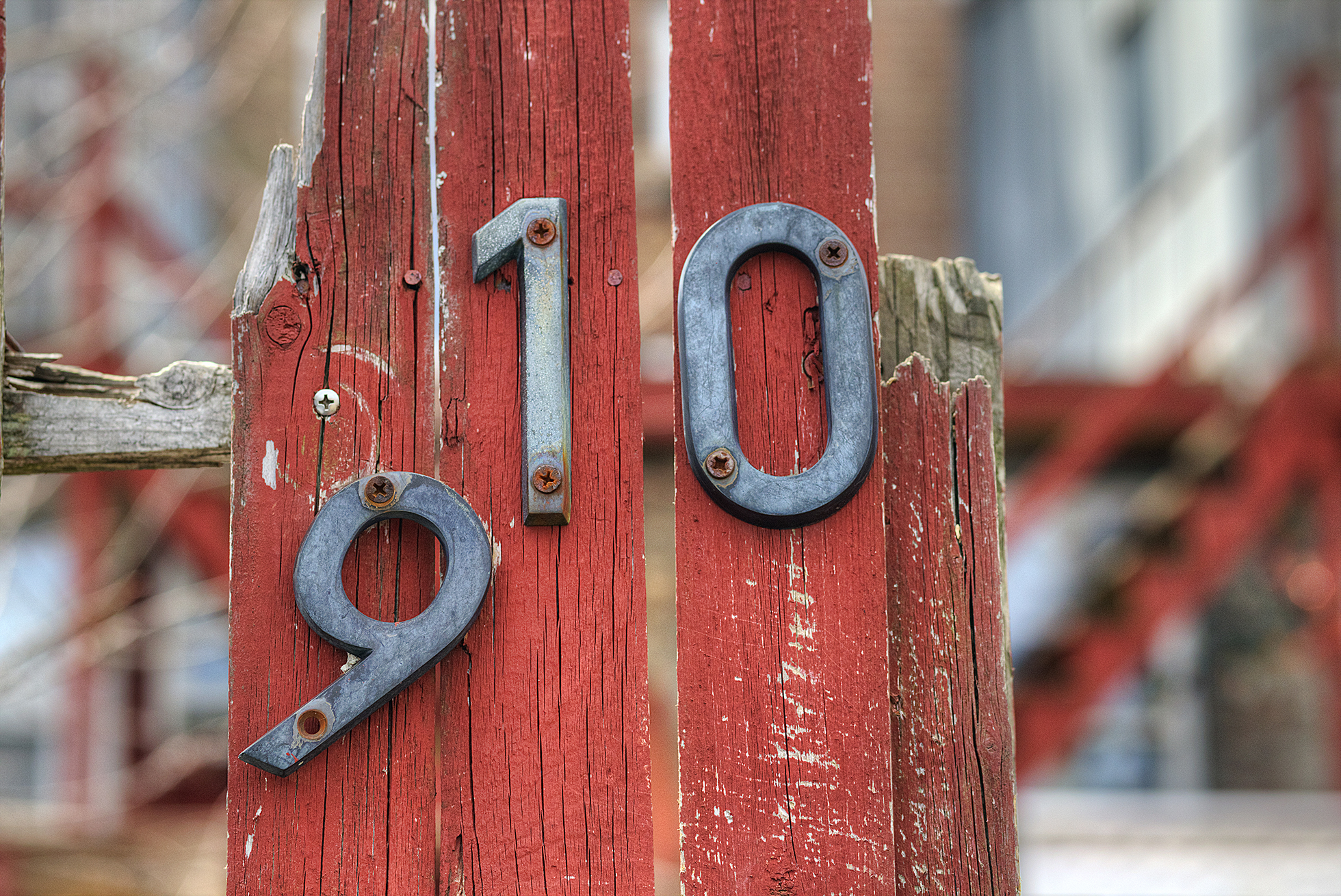 Beat up red fence with steel house numbers falling off