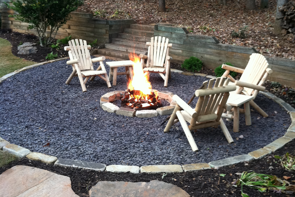 A gravel patio with fire pit, flagstone path, wood chairs