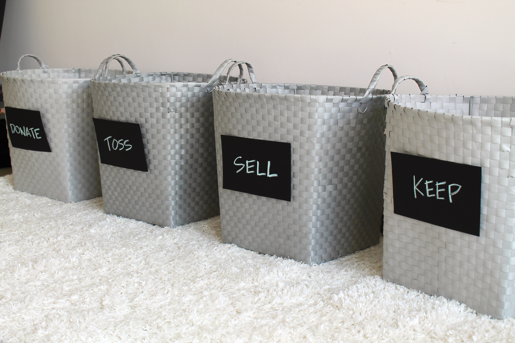 Gray bins labeled with "donate," toss," "sell," and "keep"