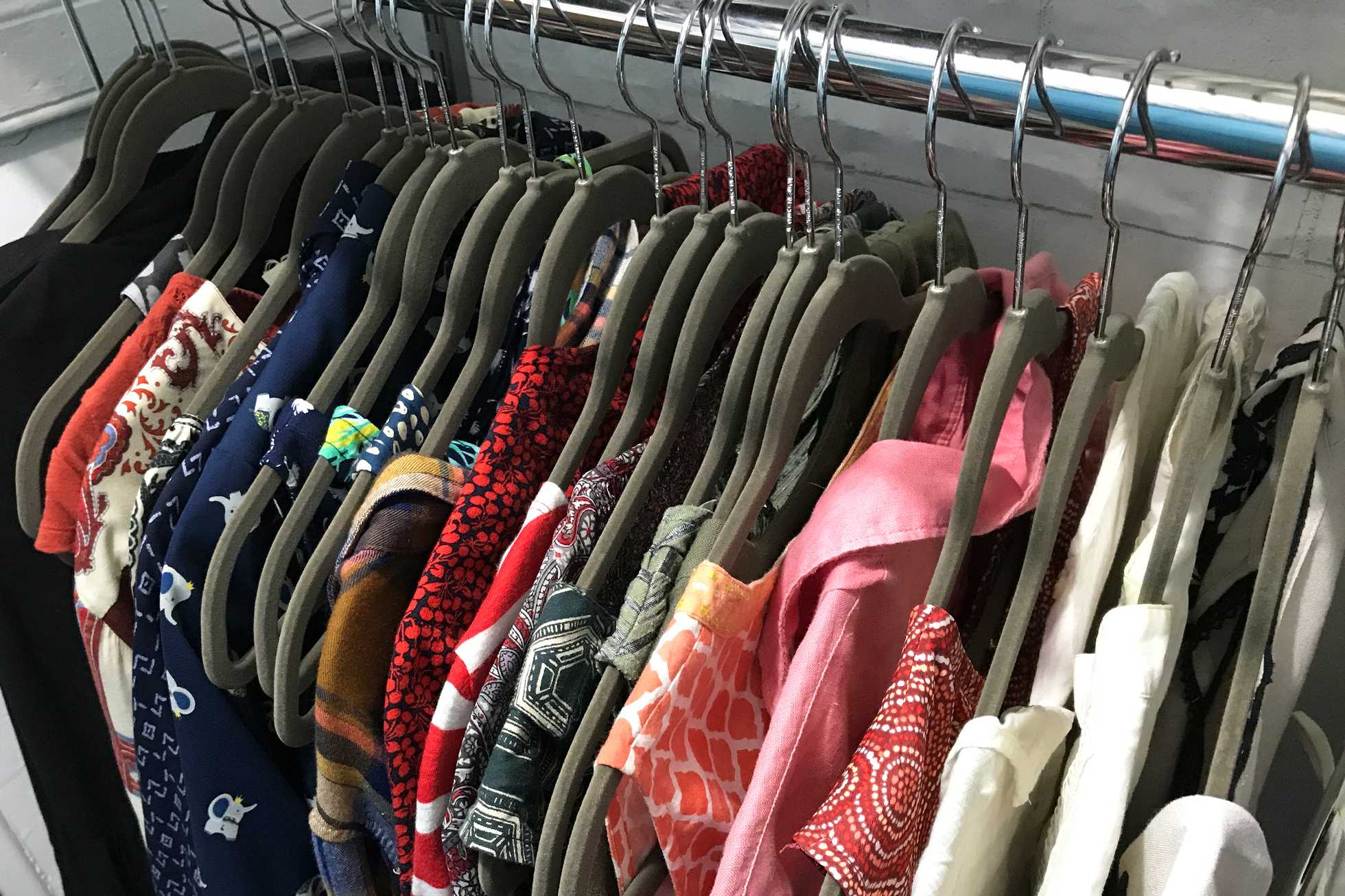 Gray felt hangers in a closet with colorful shirts